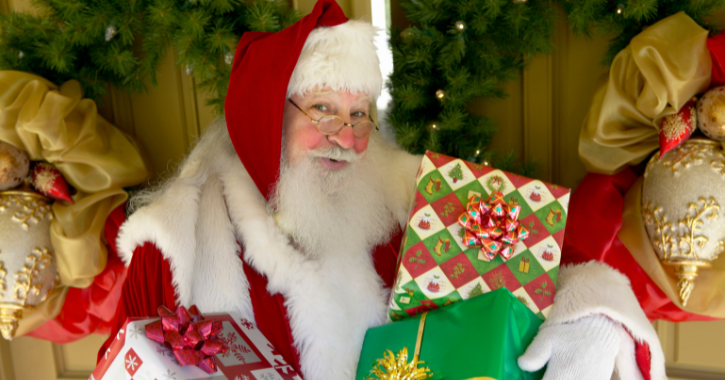 father christmas smiling at camera and holding presents